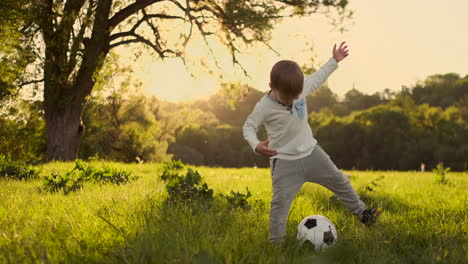In-Zeitlupe-Spielt-Der-Junge-Lustig-Mit-Einem-Fußball-Auf-Einer-Wiese-Bei-Sonnenuntergang